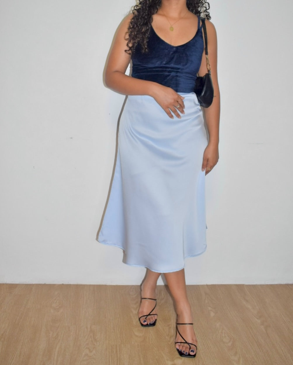Person wearing a navy top and light blue skirt against a white background