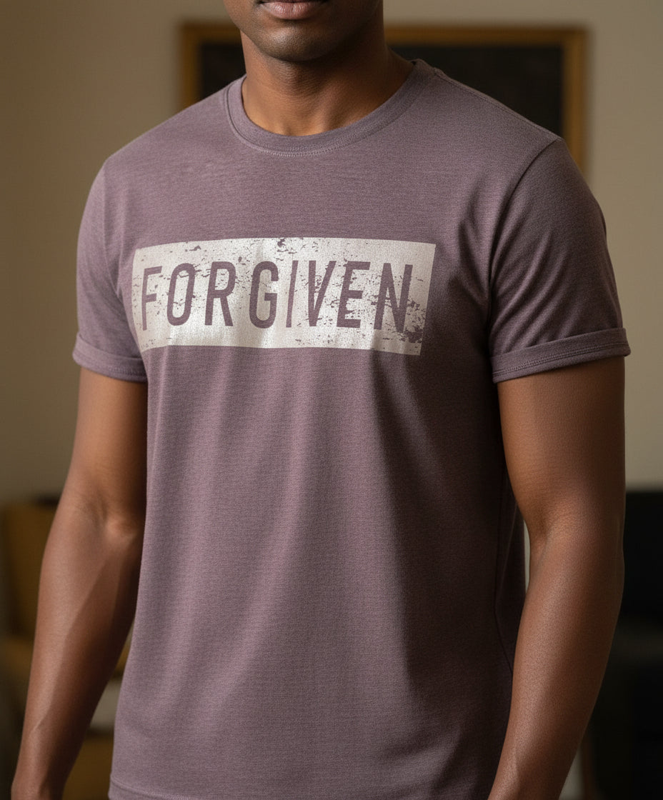 Folded t-shirt with 'FORGIVEN' text on a marble surface