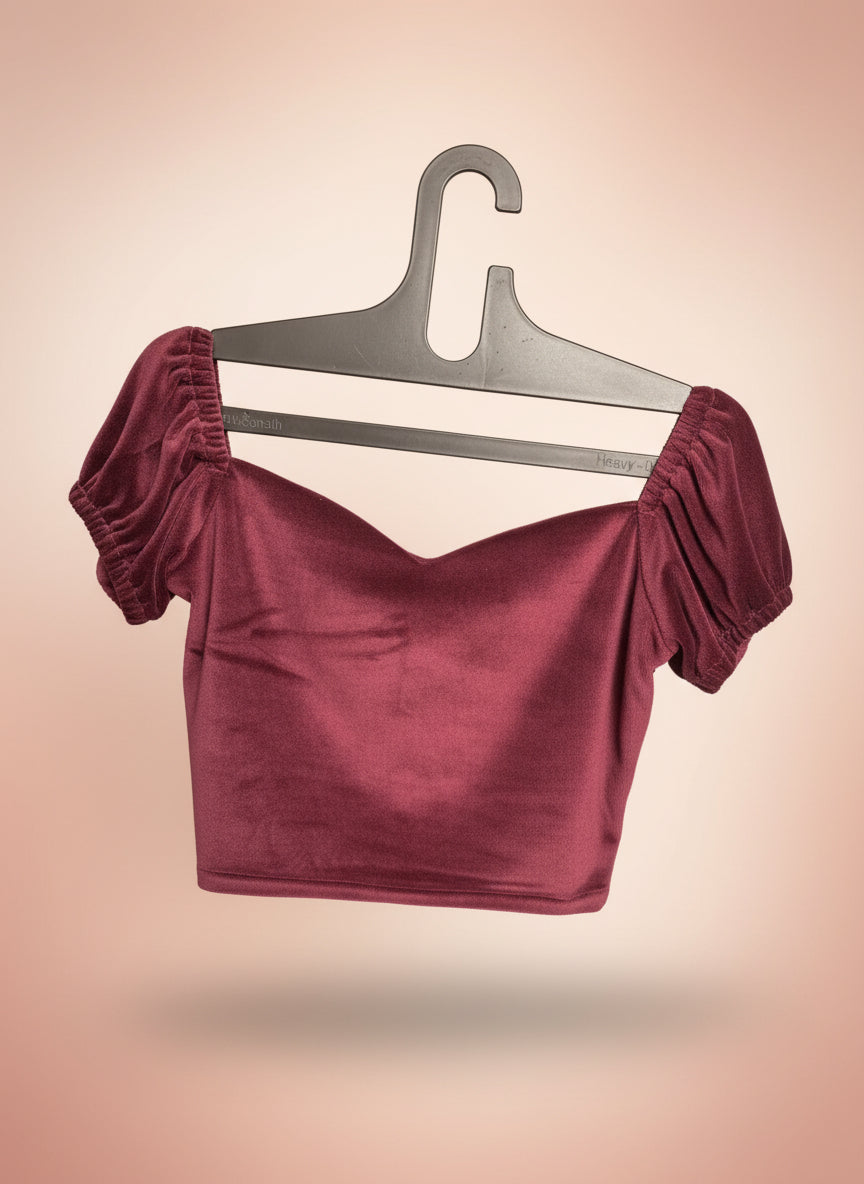 Burgundy velvet top on a gray hanger against a gradient background