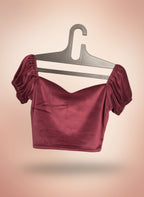 Burgundy velvet top on a gray hanger against a gradient background