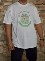 Person wearing a white t-shirt with a green logo against a brick wall.