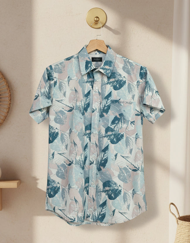 Short-sleeve shirt with a floral pattern hanging on a wooden hanger against a neutral wall.