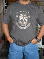 Person wearing a gray t-shirt with a palm tree design and text.