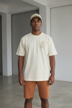 Man wearing a beige shirt and shorts standing 