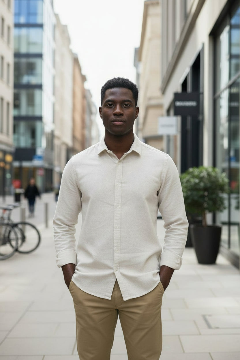 Man wearing a beige shirt and beige pants standing on a city street.