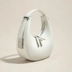 White handbag with silver accents on a beige background
