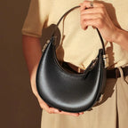 Person holding a black handbag with a neutral background