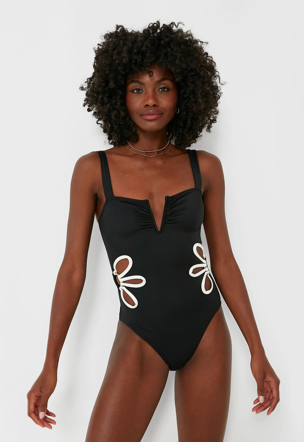 Woman wearing a black swimsuit with white floral designs on a white background