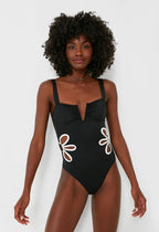 Woman wearing a black swimsuit with white floral designs on a white background