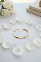 Gold bracelet flatlay with rose petals